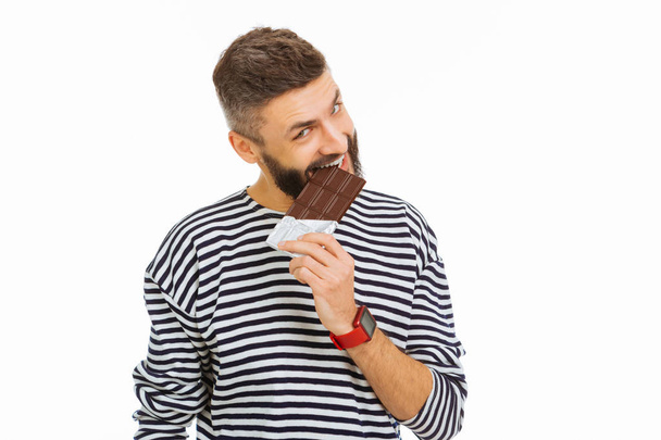 Agradable hombre atractivo comiendo una barra de chocolate
 - Foto, Imagen