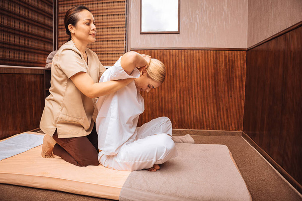 Special massage. Beautiful nice woman holding her hands up while having a special massage - 写真・画像