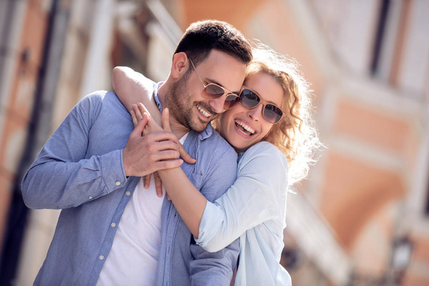 Ταξίδια, την αγάπη, ημερομηνία και άνθρωποι έννοια - ευτυχισμένο ζευγάρι αγκαλιάζει και χαμογελά στο δρόμο. - Φωτογραφία, εικόνα