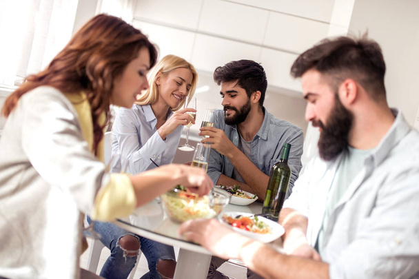 Отдых, еда, еда и напитки, люди и праздники концепция - улыбающиеся друзья обедают и пьют вино дома
. - Фото, изображение