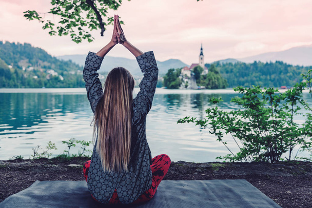 visão traseira da mulher Meditando junto ao lago
  - Foto, Imagem
