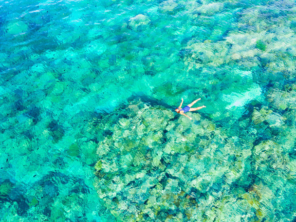 Εναέρια πάνω προς τα κάτω άνθρωποι κολύμβηση με αναπνευστήρα στον κοραλλιογενή ύφαλο τροπική Καραϊβική Θάλασσα, τιρκουάζ νερά. Αρχιπέλαγος Ινδονησία Ινδονησία Μολούκες Νήσους, τα νησιά Banda, Pulau Hatta, τουριστικά καταδυτικό ταξιδιωτικό προορισμό - Φωτογραφία, εικόνα