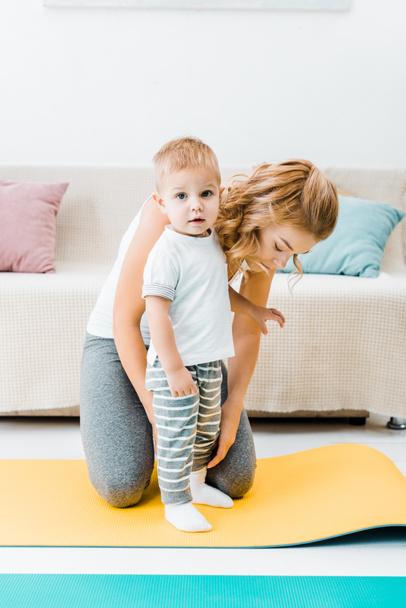 приваблива жінка і дитина малюка на фітнес килимках
 - Фото, зображення