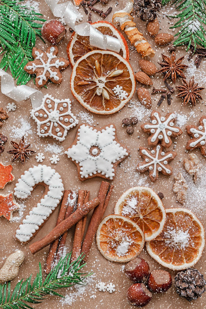 Decorazione natalizia con spezie e biscotti a forma di fiocchi di neve su sfondo di carta marrone scuro. Vista dall'alto
. - Foto, immagini
