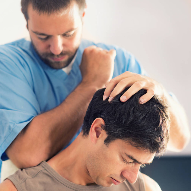 Fisioterapeuta haciendo tratamiento curativo en el cuello del hombre, Terapeuta con uniforme azul, Osteópata, Ajuste quiropráctico, concepto de alivio del dolor
 - Foto, Imagen