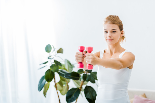 attractive woman in sportswear exercising with dumbbells at home - Fotografie, Obrázek