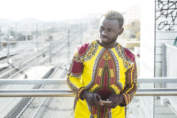 Afrikaanse zakenman met smartphone en de kleren van typische - Foto, afbeelding