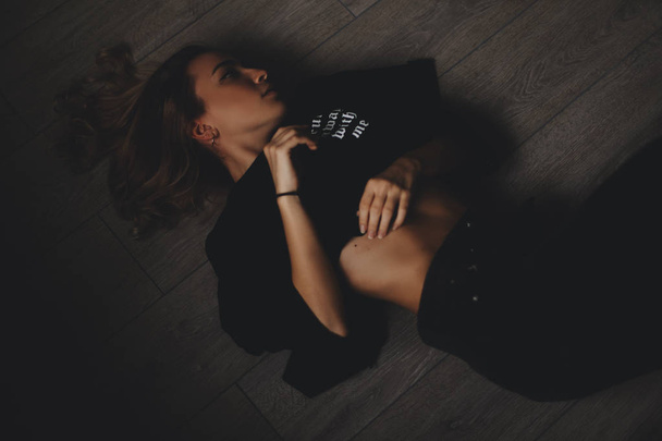Attractive sexy woman lies on the floor. She looks sensuality. Hot girl wears total black look. - Φωτογραφία, εικόνα