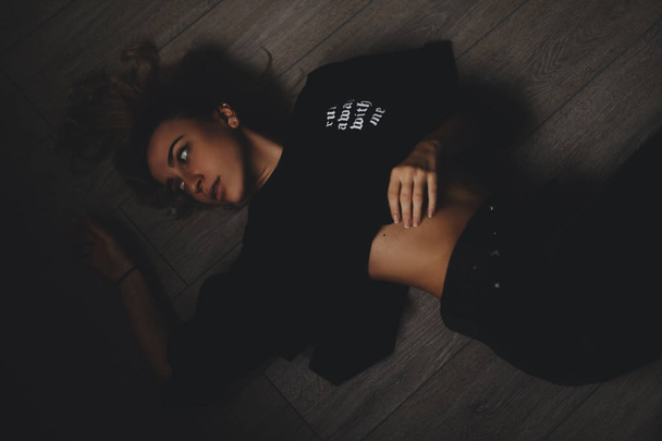 Attractive sexy woman lies on the floor. She looks sensuality. Hot girl wears total black look. - Foto, Imagem