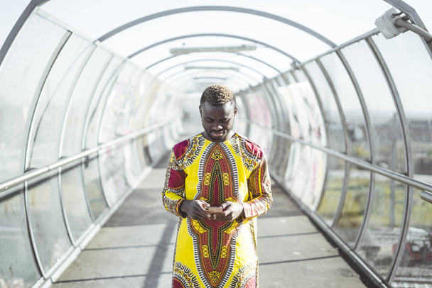 Empresário africano com smartphone e as roupas de típico
 - Foto, Imagem
