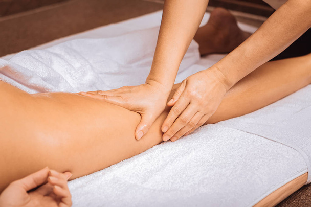 Professional female masseuse touching her clients leg - Fotó, kép