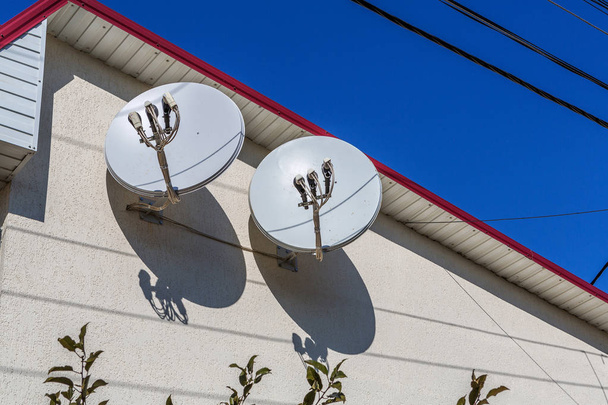Antena satelitarna na ścianie budynku mieszkalnego z błękitnego nieba - Zdjęcie, obraz
