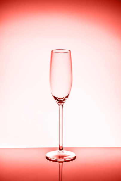 Copa de champán en el fondo de luz.. Concepto de cristalería fina. Vertical. Tema coral vivo - color del año 2019
 - Foto, imagen