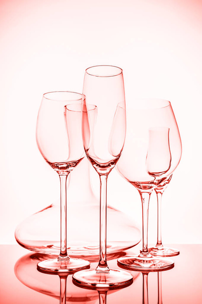 Glasauswahl mit Wein, Champagner, Likörgläsern und Dekanter auf hellem Hintergrund.. Konzept feiner Kristallgläser. Vertikal. lebende Korallen Thema - Farbe des Jahres 2019 - Foto, Bild