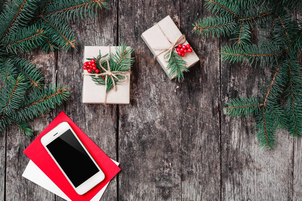 スマート フォン、クリスマス ギフト、モミの枝で木製の背景上のモミの枝でクリスマスの背景。クリスマスと新年あけましておめでとうございますの組成物。フラット横たわっていた、トップ ビュー - 写真・画像