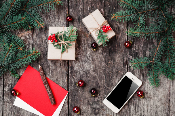 Sfondo natalizio con smartphone, regalo di Natale, rami di abete su sfondo di legno con rami di abete. Natale e Felice Anno Nuovo composizione. Posa piatta, vista dall'alto
 - Foto, immagini