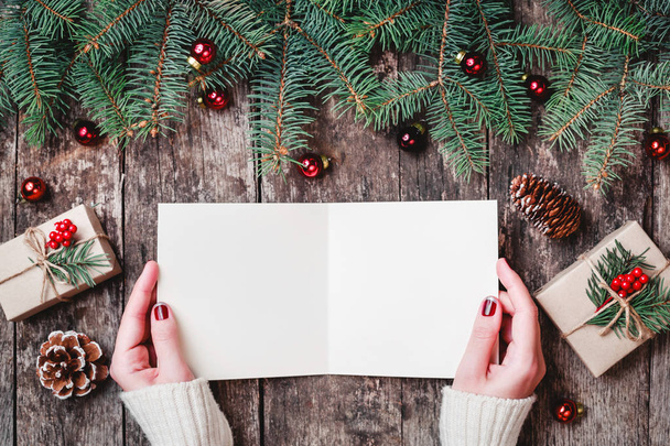Ręka pisania i czytania list do Santa na drewniane tła z prezenty, gałęzie jodły i cukierki. Boże Narodzenie i nowy rok karty. Widok płaski świeckich, top - Zdjęcie, obraz