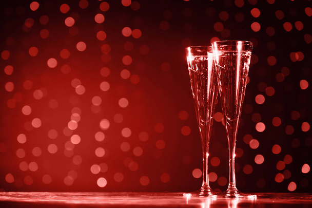 Two glasses of champagne on dark bokeh background. Holiday concept. Festive bokeh background. Horizontal, toned, lilac tone. Living coral theme - color of the year 2019 - Photo, Image