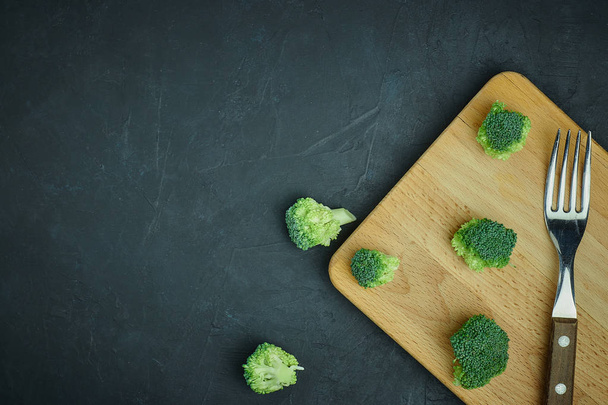 placer green broccoli segments from a small bucket. Healthy eating pattern on dark background. Copy space Top view. Vegetarian food. - Fotó, kép