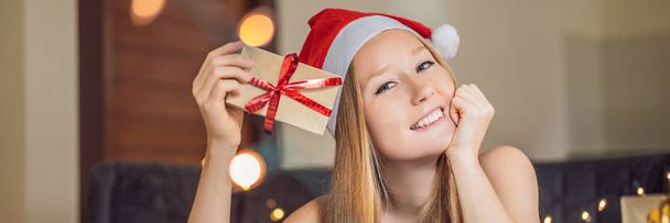 Young woman posing with present wrapped in craft paper for Christmas - Foto, imagen