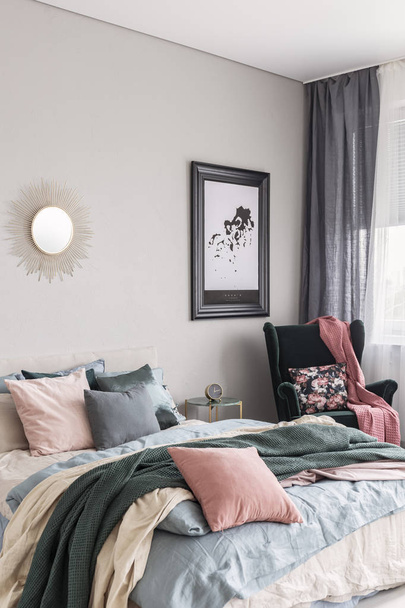 Sun shape like mirror and map in black frame on grey wall of fashionable bedroom interior with king size bed with cozy bedding - 写真・画像