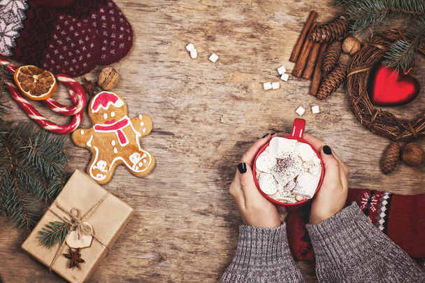 Dárek, kornouty, dárky, kafe, kakao. Vánoce, novoroční zázemí. Ženská ruka drží šálek. Zima, Nový rok, vánoční zátiší.  - Fotografie, Obrázek