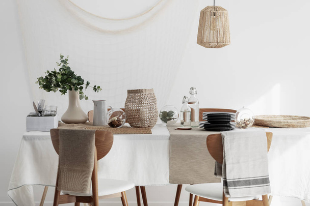 Natural dining room with linen napkins, white tablecloth and wicker lamp - Foto, Imagen
