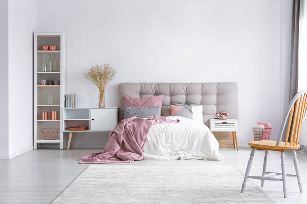 White rug on the floor of bright bedroom interior with comfortable bed with headboard and white wooden furniture - Zdjęcie, obraz