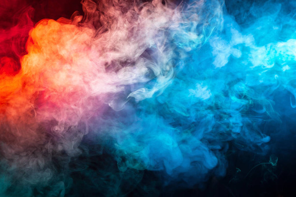 A blast of smoke evaporating in the colors of the rainbow: red, orange, yellow, green, cyan, magenta against a dark background. - Foto, afbeelding