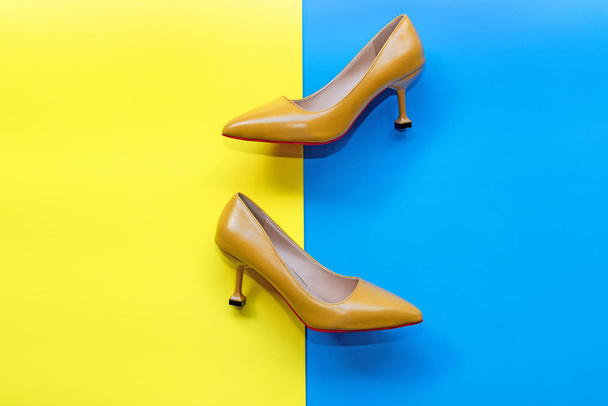 Fashion woman accessories set. Trendy yellow fashion shoes heels. blue and yellow pastel color background. Fashion Concept. - Fotó, kép