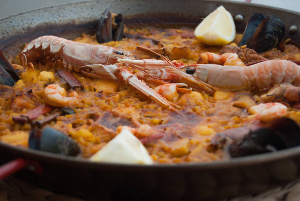 O prato típico espanhol Paella com arroz mexilhões camarão datas e duas cunhas de limão
 - Foto, Imagem