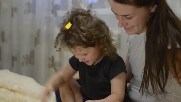 child is playing with paper and smiles genuinely on his mother. Slow video - Séquence, vidéo