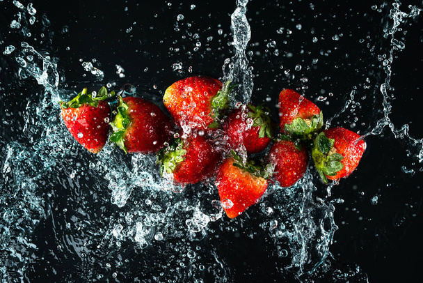 Aardbeien Water Splash op zwarte achtergrond - Foto, afbeelding