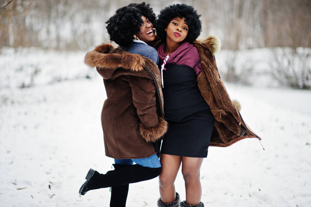 Two curly hair african american woman wear on sheepskin coat and gloves posed at winter day. - Φωτογραφία, εικόνα
