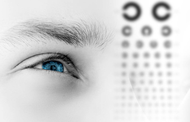 menschliches männliches blaues Auge aus nächster Nähe, Überprüfung des menschlichen Sehvermögens, Alphabetdiagramm, Tabelle - Foto, Bild