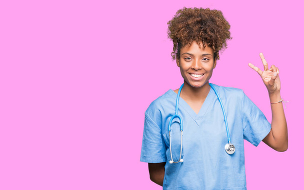 Молодий афроамериканець лікар жінка над ізольованих фон показ і вказуючи з пальцями номер два, а посміхаючись впевненими і щасливими. - Фото, зображення