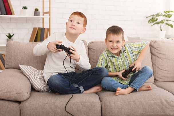 Маленькі хлопчики грають в ігрову консоль вдома
 - Фото, зображення