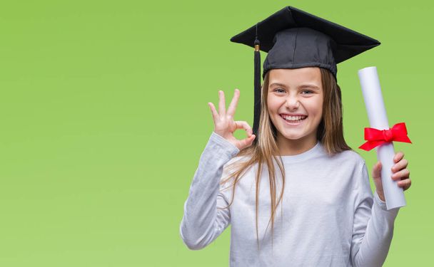 Jovem menina bonita vestindo pós-graduação cap segurando grau sobre fundo isolado fazendo sinal ok com os dedos, excelente símbolo
 - Foto, Imagem
