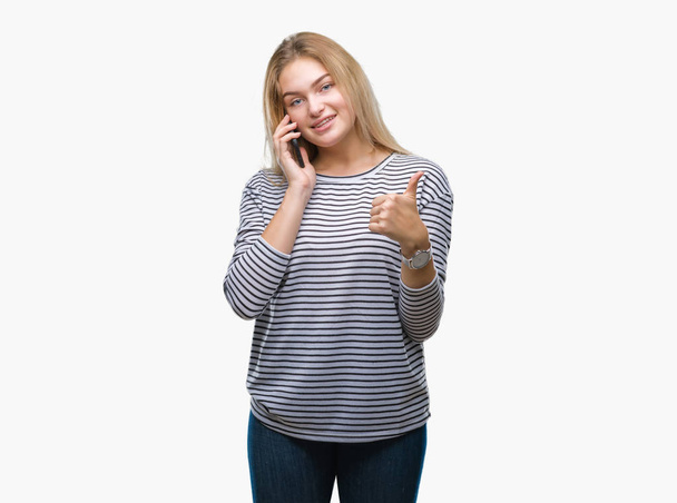 Mujer joven caucásica que muestra la pantalla del teléfono inteligente sobre un fondo aislado feliz con una gran sonrisa haciendo signo de ok, pulgar hacia arriba con los dedos, señal excelente
 - Foto, imagen