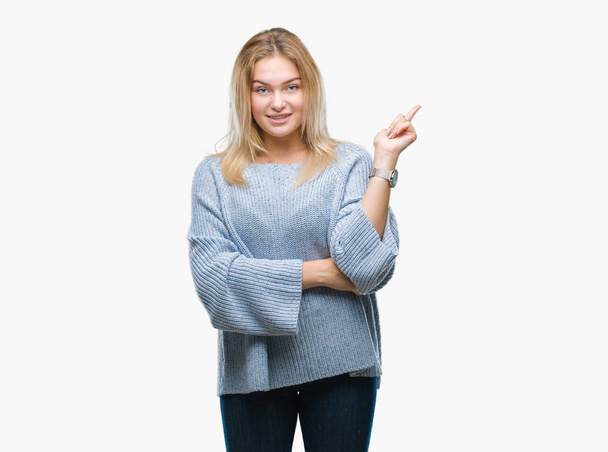 Młoda kobieta kaukaski swetrze zima na białym tle z wielkim uśmiechem na twarzy, wskazując z dłoni i palców z boku patrząc na kamery. - Zdjęcie, obraz