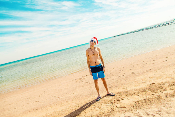 A man in a santa hat on the beach. Selective focus. holidays. - Photo, Image