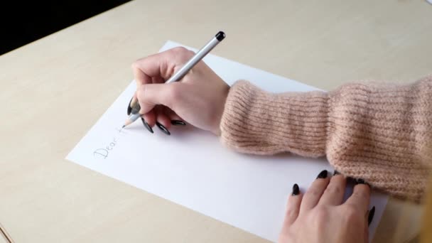 Mulher escrevendo uma carta com um lápis em uma mesa em casa
 - Filmagem, Vídeo