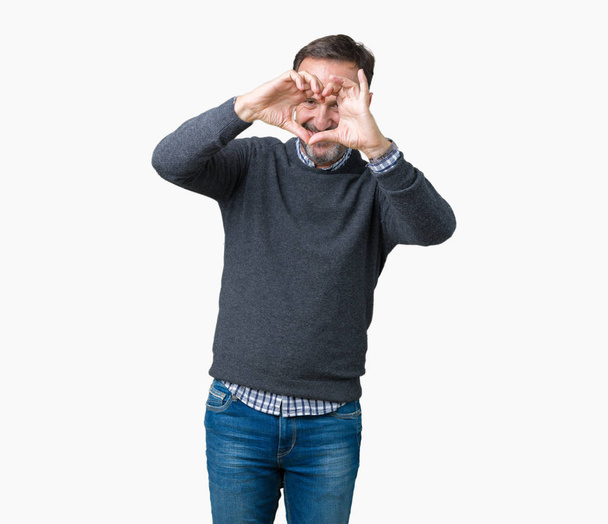 Hombre mayor de mediana edad guapo usando un suéter sobre un fondo aislado haciendo forma de corazón con la mano y los dedos sonriendo mirando a través del signo
 - Foto, imagen