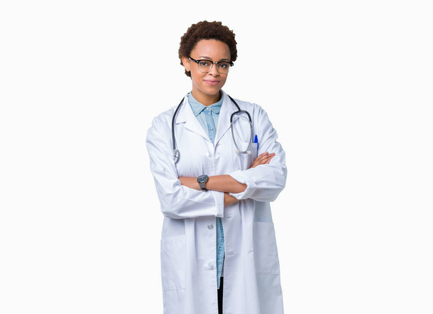 Jeune femme médecin afro-américaine portant un manteau médical sur fond isolé heureux visage souriant avec les bras croisés regardant la caméra. Personne positive
. - Photo, image