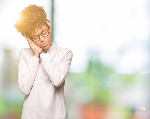Beautiful young african american woman wearing glasses over isolated background sleeping tired dreaming and posing with hands together while smiling with closed eyes. - Photo, Image