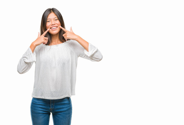 Mladá asijská žena izolované pozadí s úsměvem sebevědomá ukazující a ukazující prsty zuby a ústa. Koncepce zdraví. - Fotografie, Obrázek