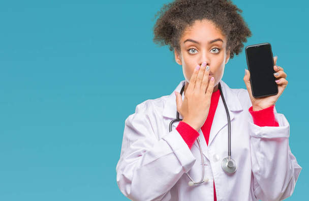 Kobieta młody afro amerykański lekarz za pomocą smartfona na na białym tle okładka usta ręką szoku ze wstydem za błąd, wyrażenie strachu, boi się w milczeniu, tajne koncepcja - Zdjęcie, obraz