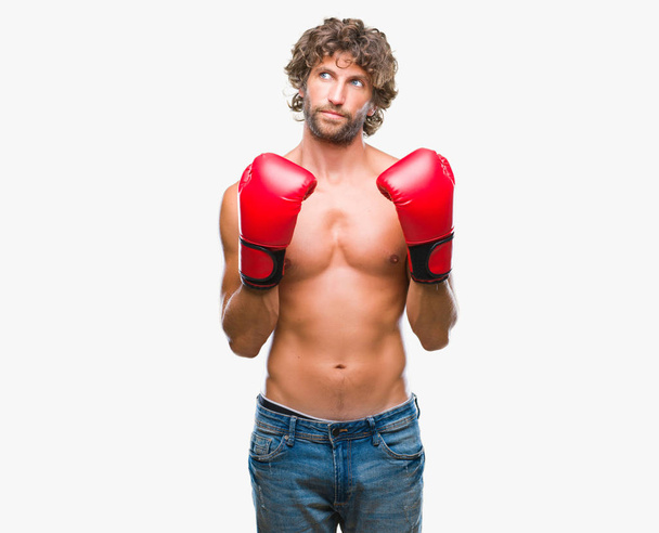 Hombre guapo boxeador hispano usando guantes de boxeo sobre fondo aislado sonriendo mirando al lado y mirando hacia otro lado pensando
. - Foto, imagen