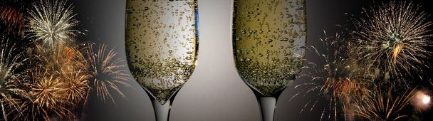 Two glasses of wine sizzling champagne with bubbles close-up on the background of colorful fireworks - Foto, Imagem