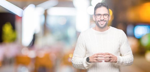 Young handsome man wearing glasses over isolated background Hands together and fingers crossed smiling relaxed and cheerful. Success and optimistic - Фото, зображення